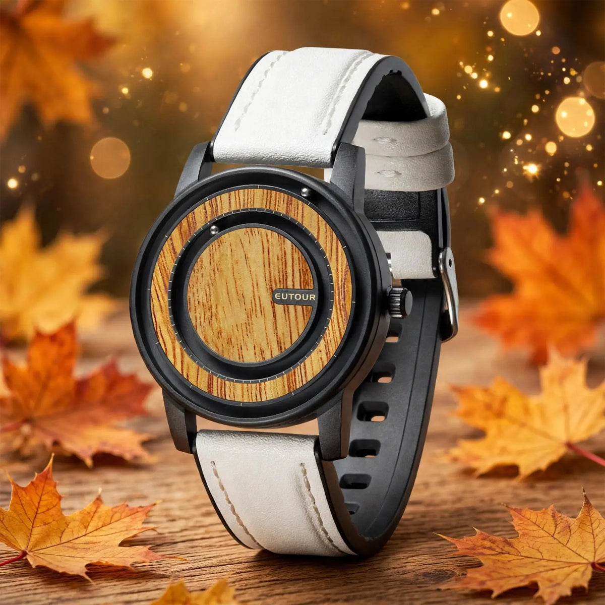 EUTOUR magnetic ball watch with light maple wood dial and white leather strap standing on wooden table with autumn maple leaves and golden bokeh lights background, EUTOUR logo visible on dial