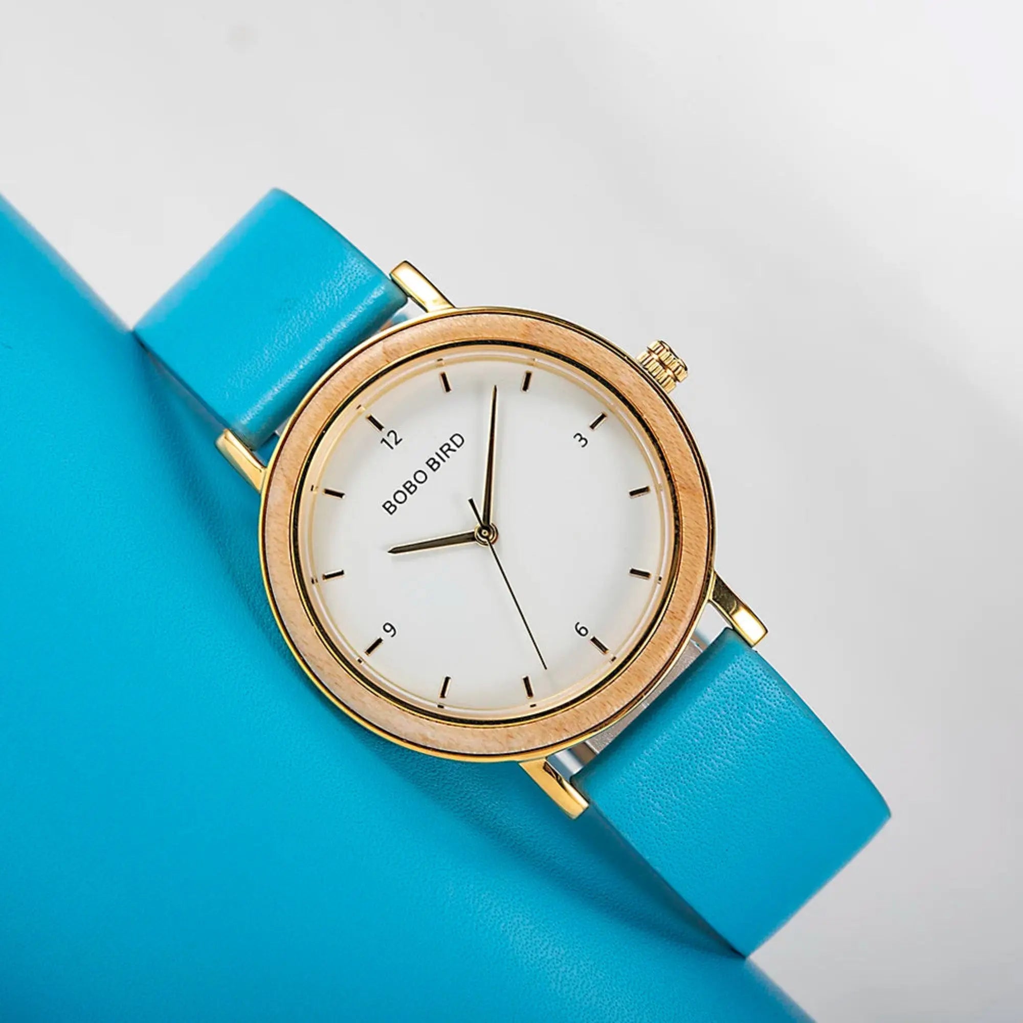 A BoBo Bird women's watch with a pink leather band and a gold-colored case, displayed on a white furry surface.
