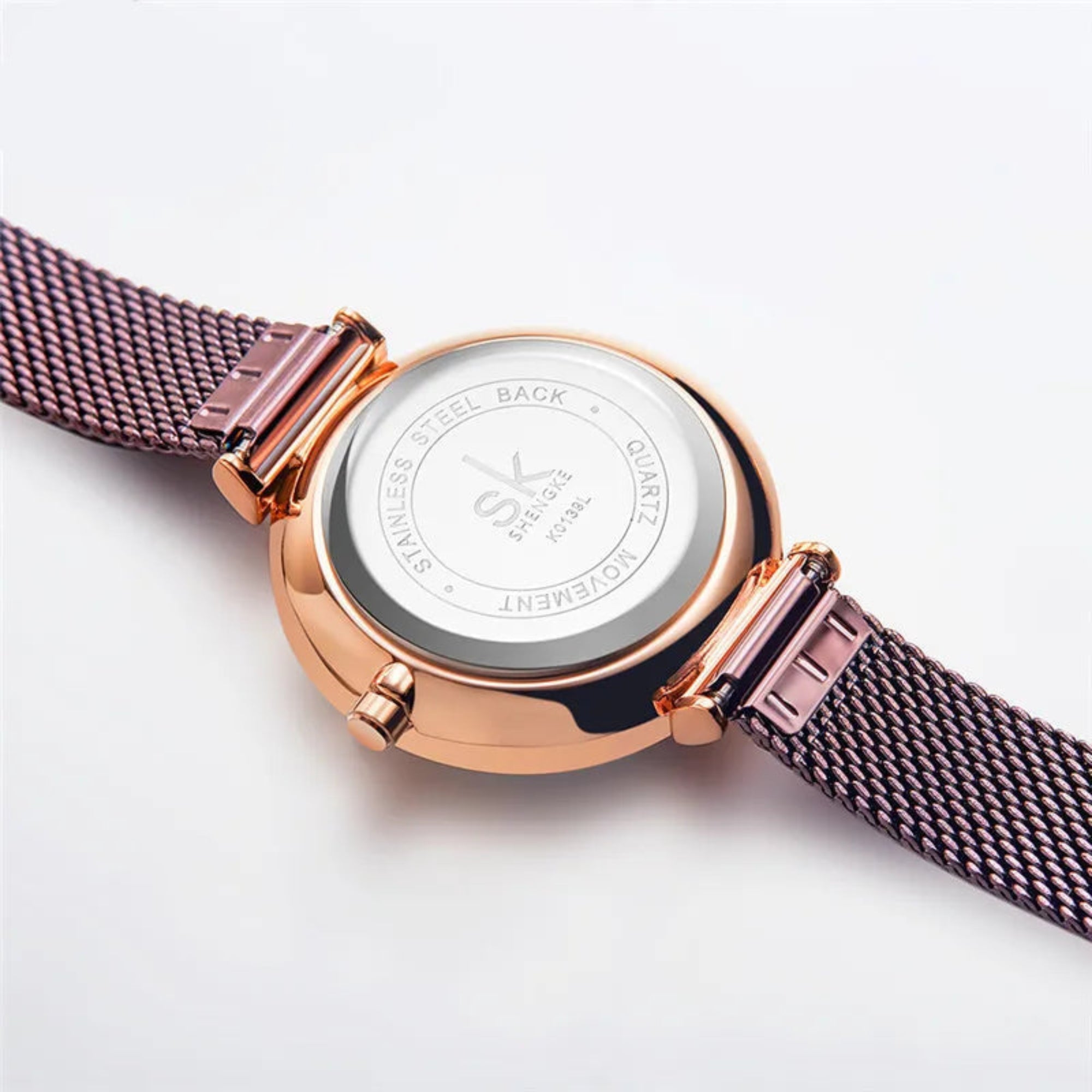 Rose gold watch with mesh band on a white background