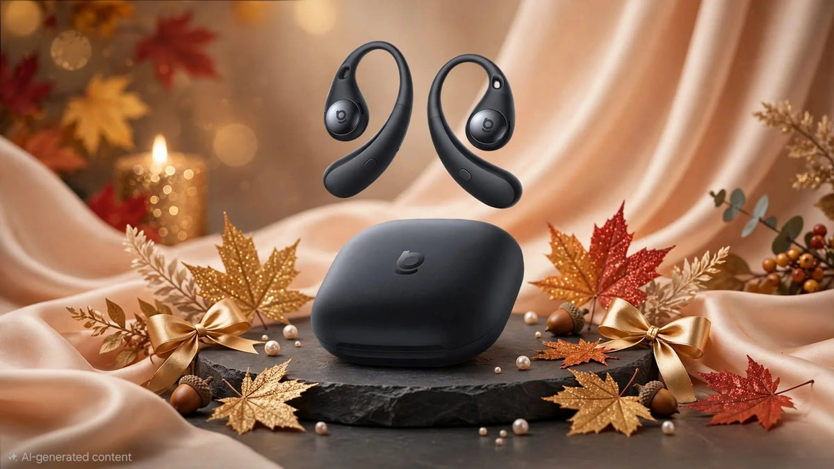 Midnight black open-ear wireless earbuds floating above matching black charging case on black slate stone platform, with beige silk fabric background, golden glitter maple leaves, red glitter leaves, gold satin bows, acorns, pearls, and warm candle bokeh lights, autumn luxury gift decoration