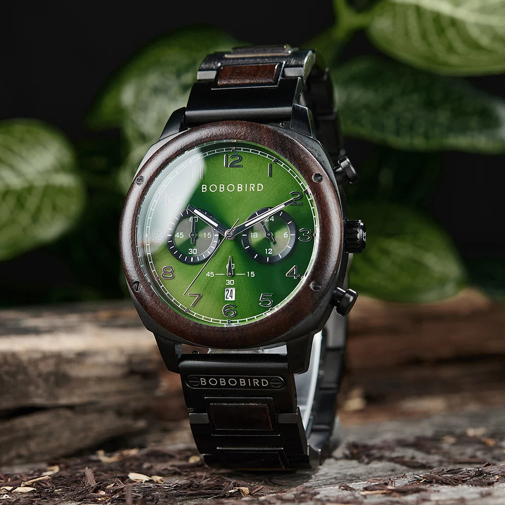 Bobobird men's chronograph watch with a green dial, dark wood-tone bezel, and black metal case and strap, displayed on a rustic log with green leaves in the background.