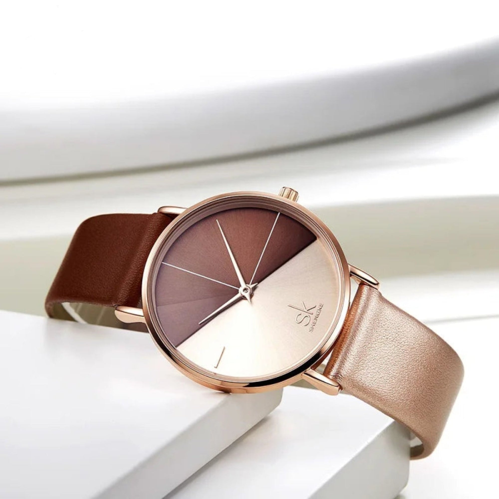 Watch with brown strap and rose gold case on a white background