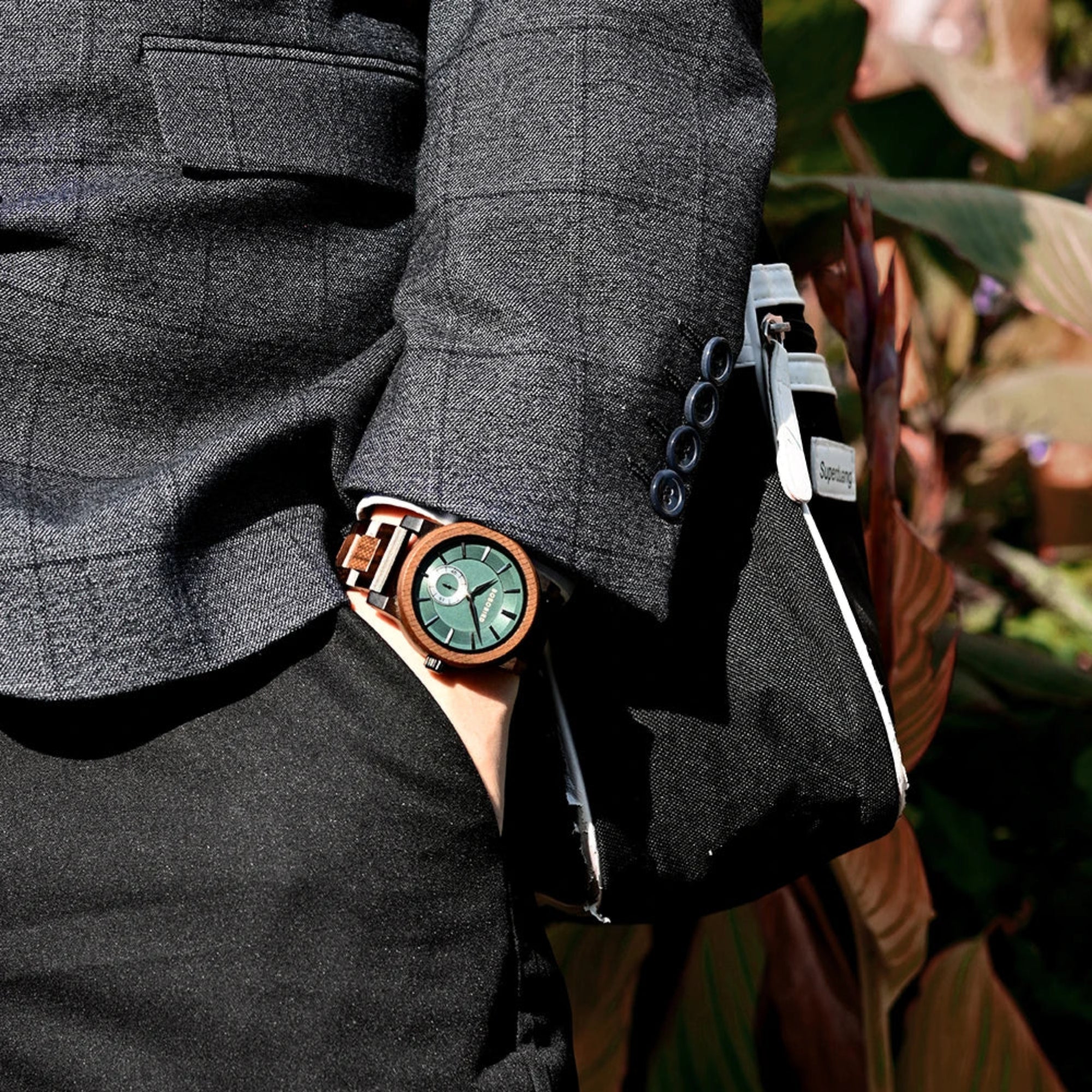 Person wearing a dark gray suit with a wooden watch on a blurred background