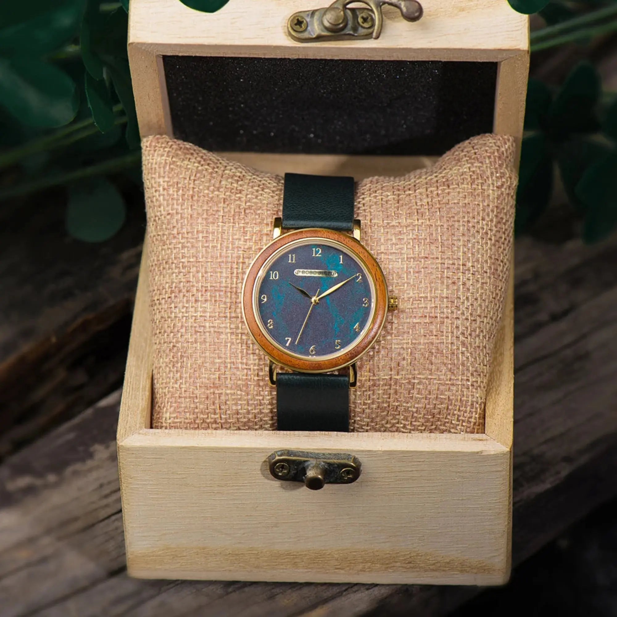 Watch with blue face and black strap in a wooden box on a wooden surface