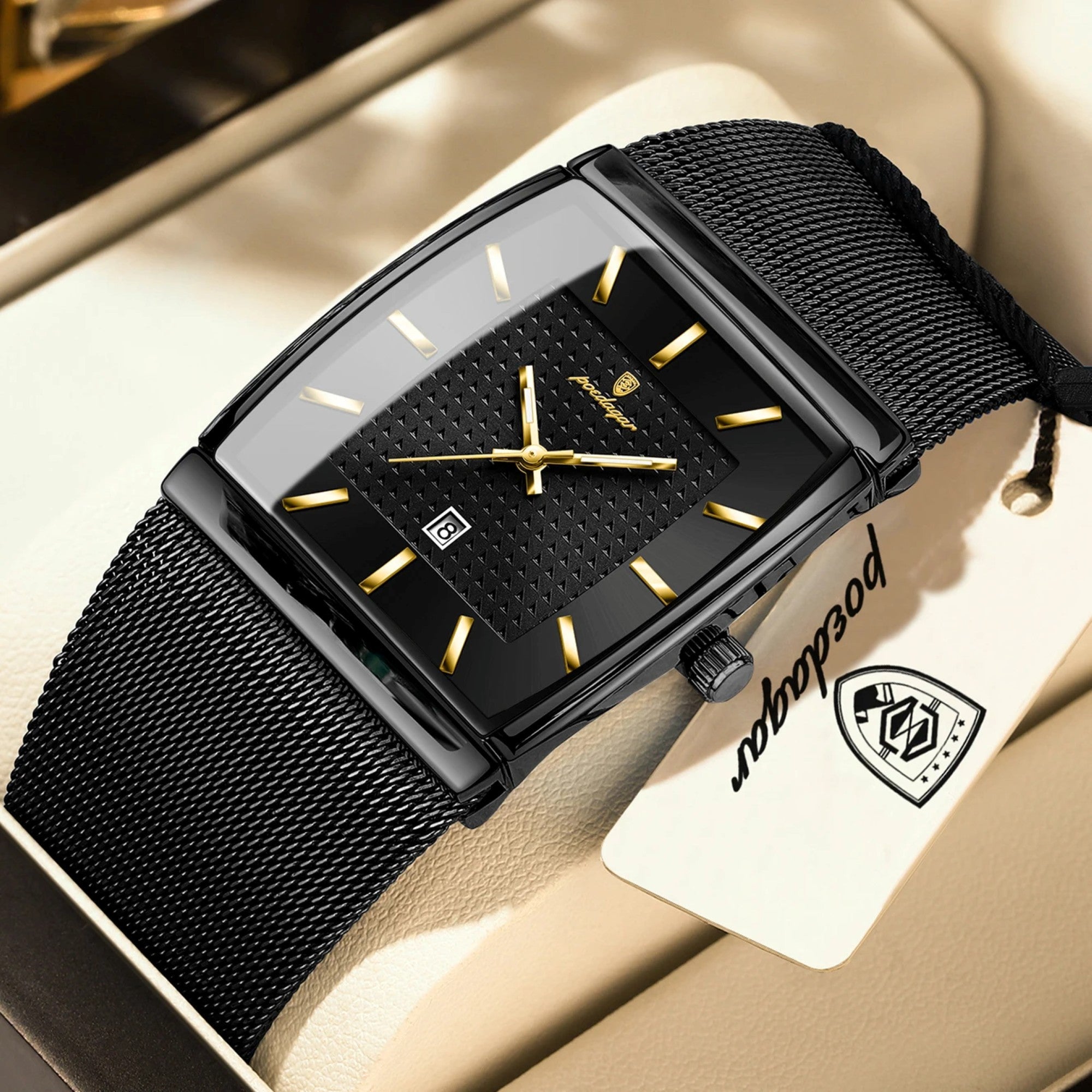Black wristwatch with gold accents on a beige surface, featuring a brand tag.