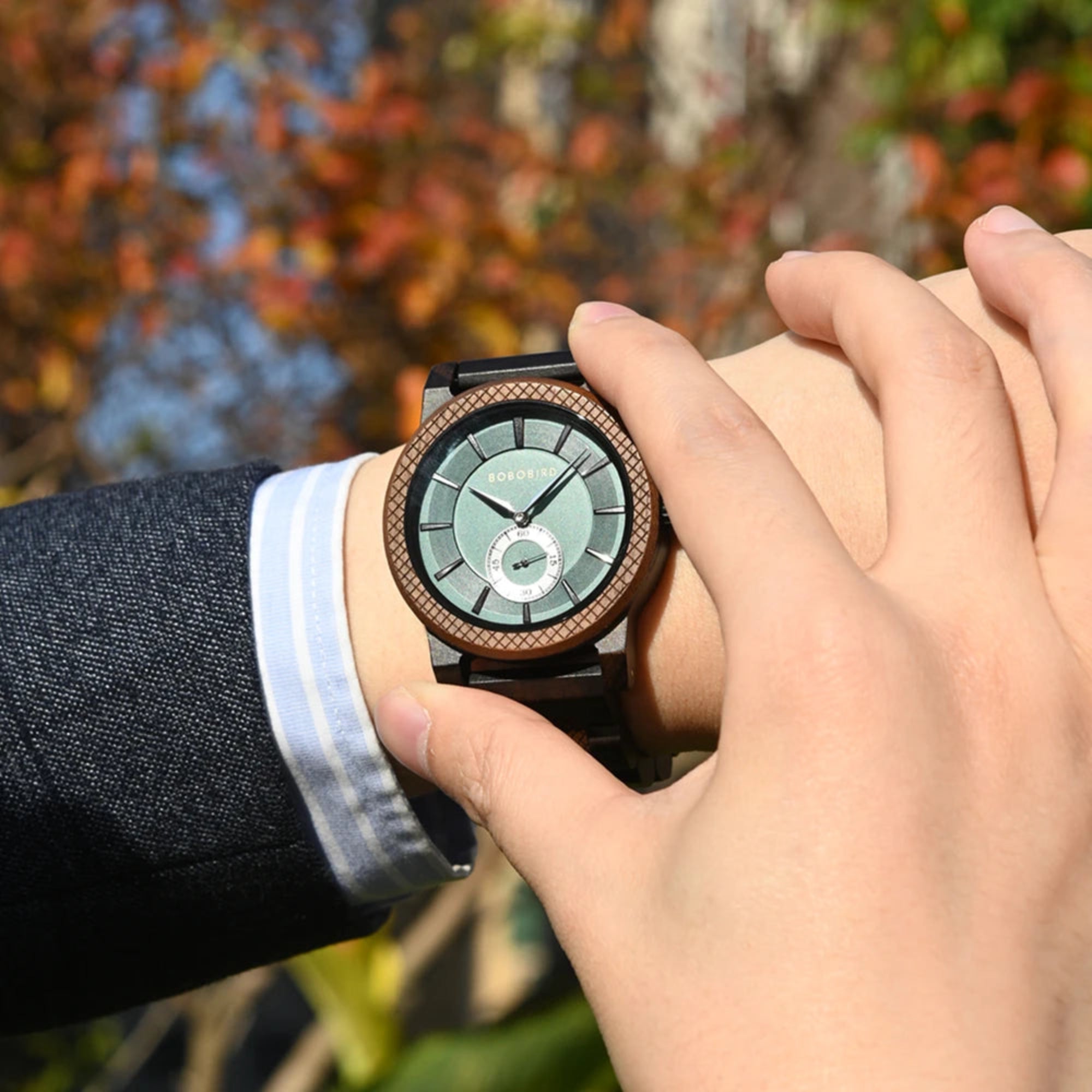 Person wearing a stylish watch with a blurred natural background