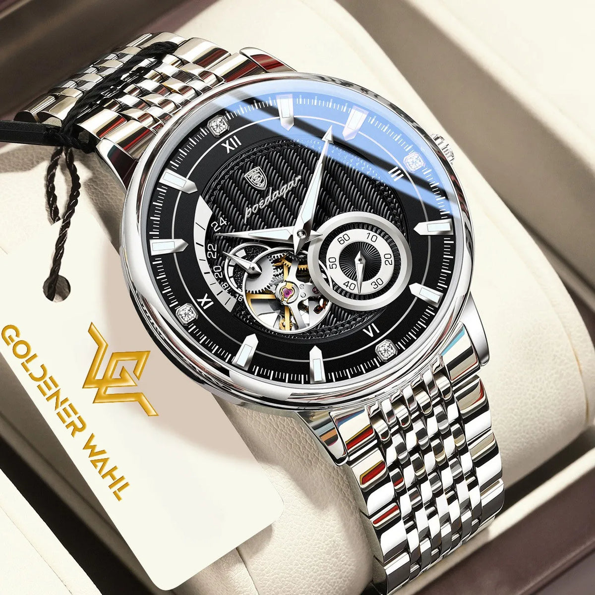 Goldener Wahl automatic mechanical watch with a silver stainless steel link bracelet, black dial, and skeletonized movement visible at the 6 o'clock position, presented in its cream-colored box with a branded hangtag.