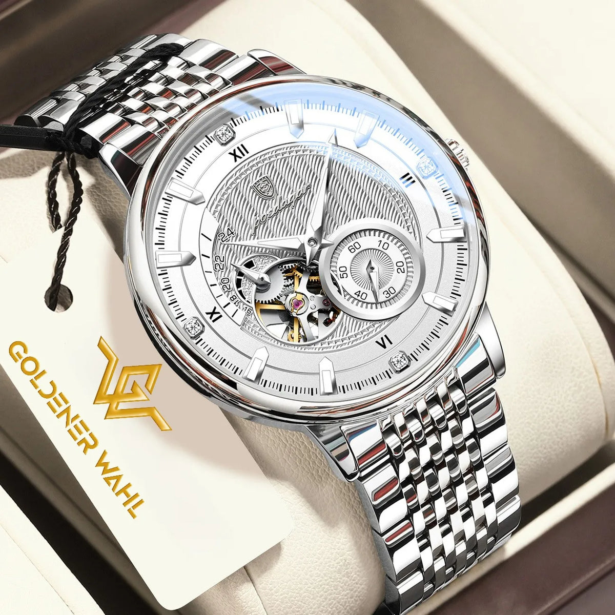 A luxury skeleton wristwatch with a silver stainless steel link bracelet and a detailed silver dial, presented inside its cream-colored gift box. A branded paper tag reading 'GOLDENER WAHL' is visible on the left.
