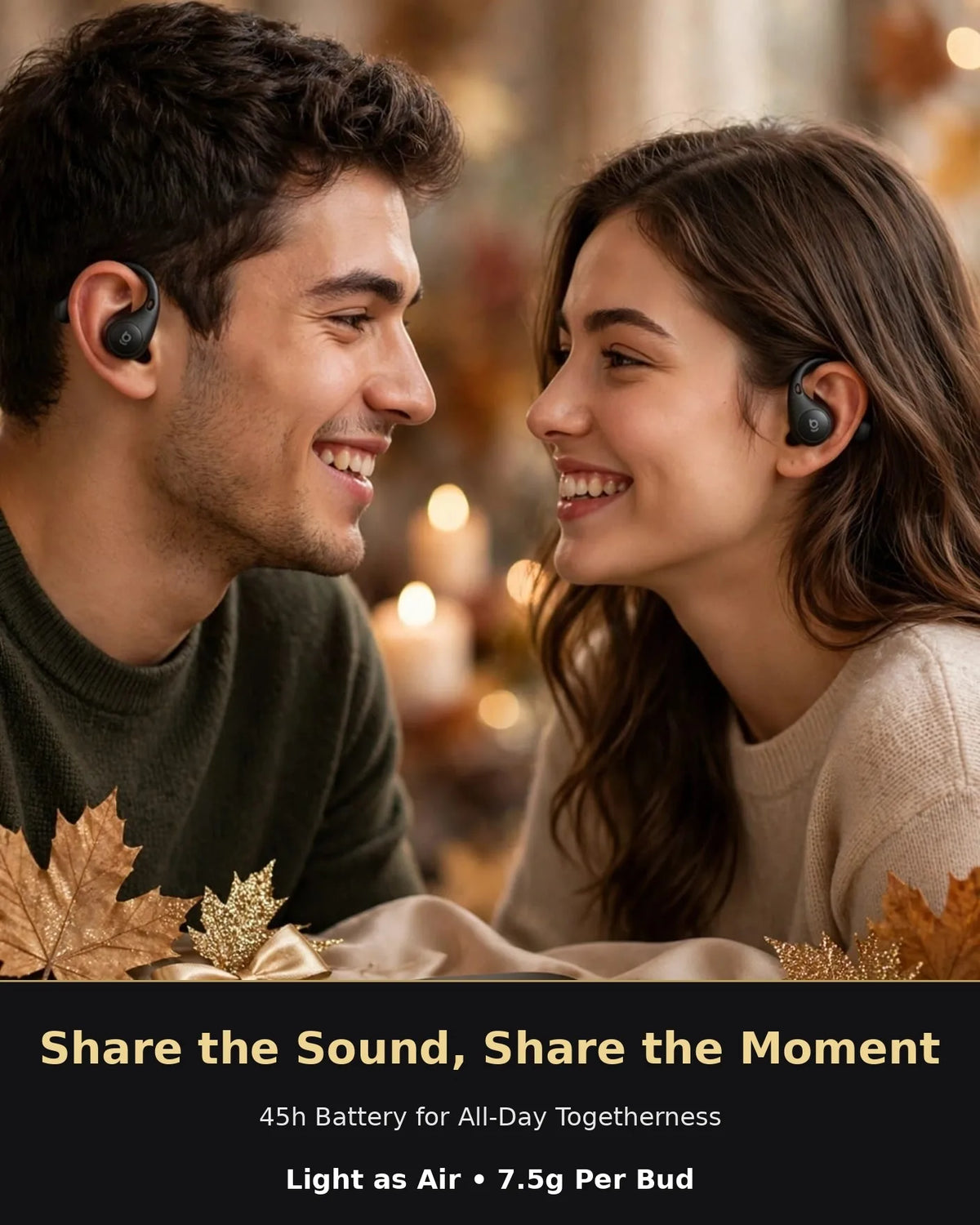 Happy young couple smiling at each other wearing black Baseus Eli Sport 2 open-ear earbuds correctly with S-Curve hook behind ear in cozy autumn luxury setting with black oval case on slate, gold glitter leaves and candles