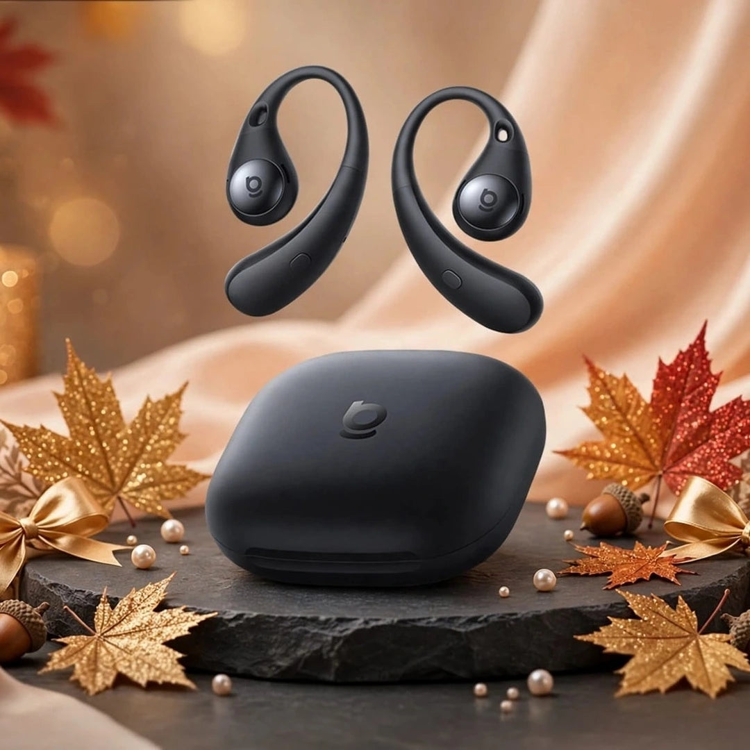 Black Baseus Eli Sport 2 open-ear earbuds floating above black oval charging case on black slate stone with gold glitter maple leaves, gold bows, acorns and pearls