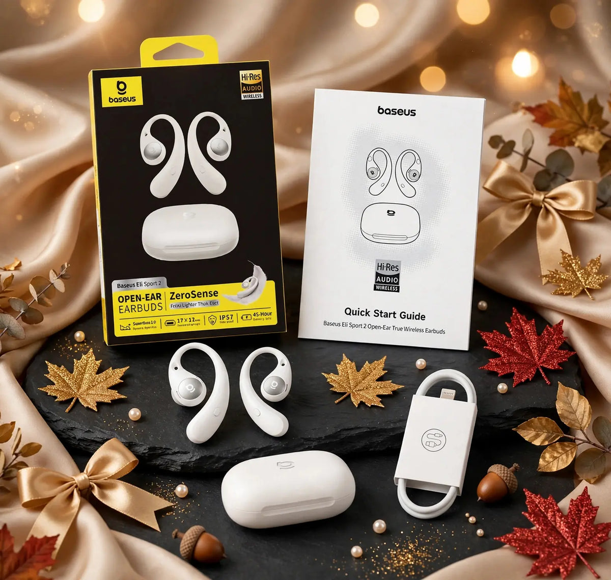 Baseus Eli Sport 2 open-ear earbuds white unboxing with retail box, quick start guide, two S-Curve earbuds, oval charging case and USB cable on black slate stone with gold maple leaves, satin bows, pearls and warm bokeh lights