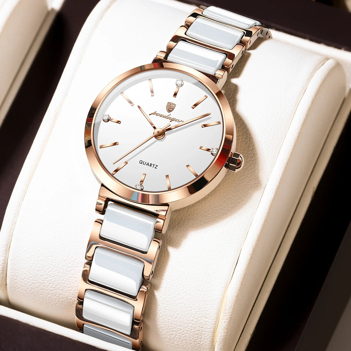 A women's quartz wristwatch with a white dial, rose gold case, and white ceramic links, displayed on a cream-colored watch box.