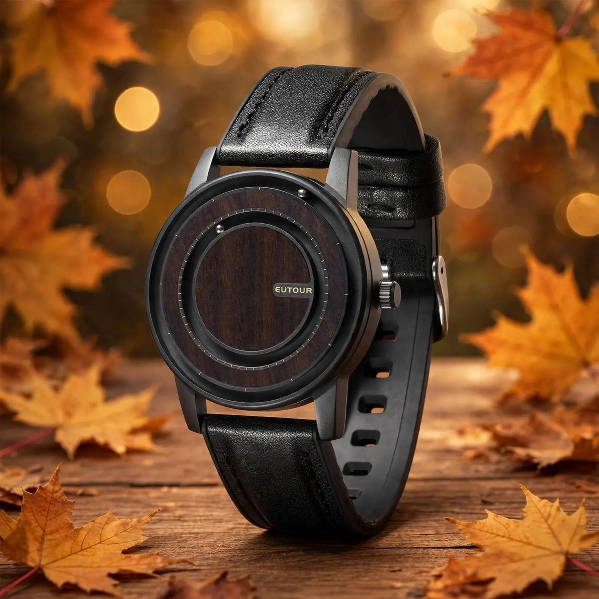 EUTOUR magnetic ball watch with dark ebony wood dial and black leather strap on wooden table surrounded by golden autumn maple leaves