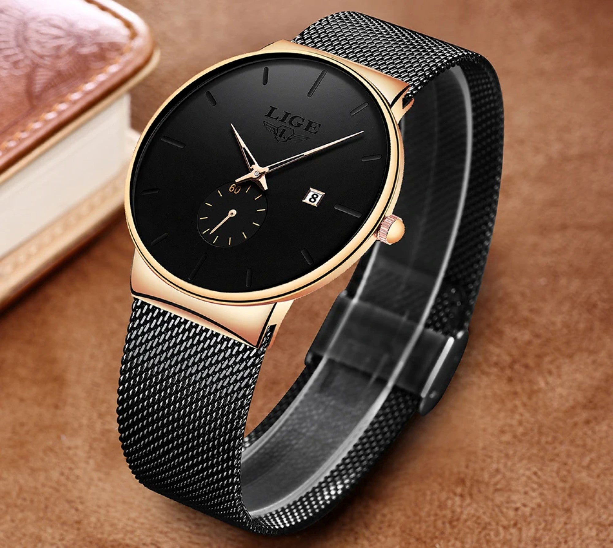 Black and gold watch with mesh band on a brown background