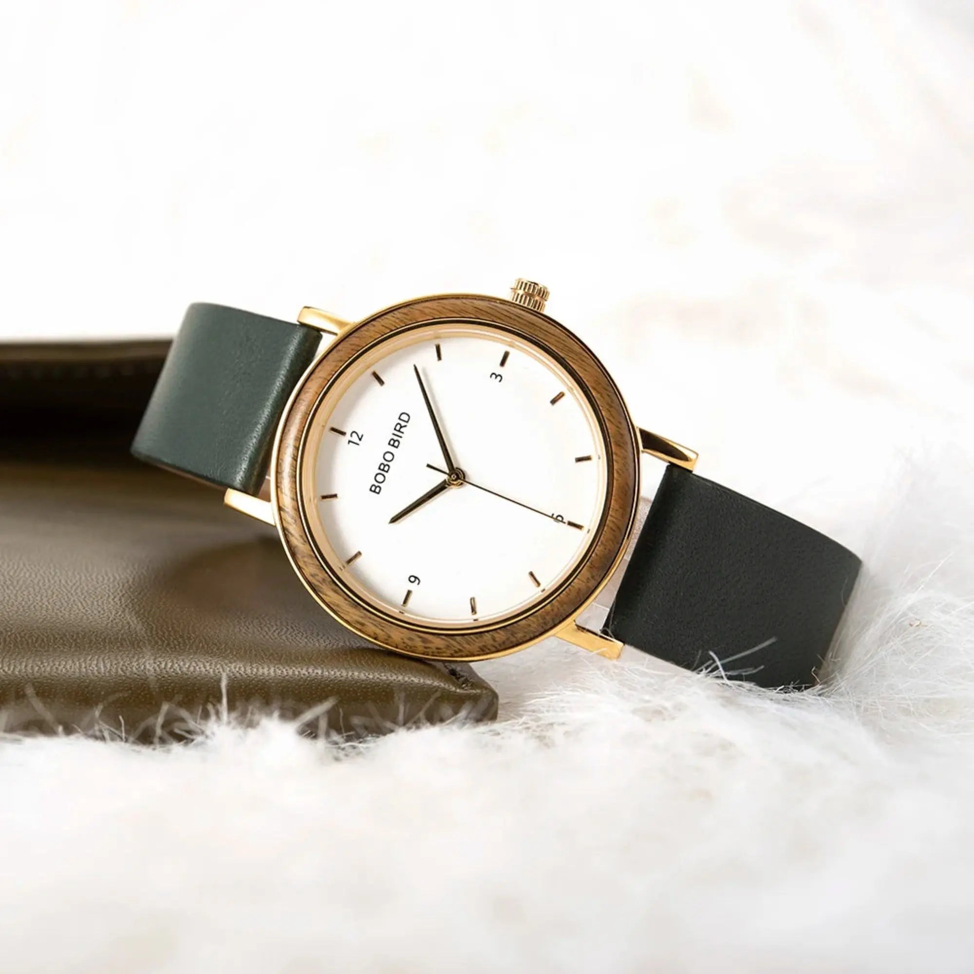 Watch with a gold case and green strap on a white background