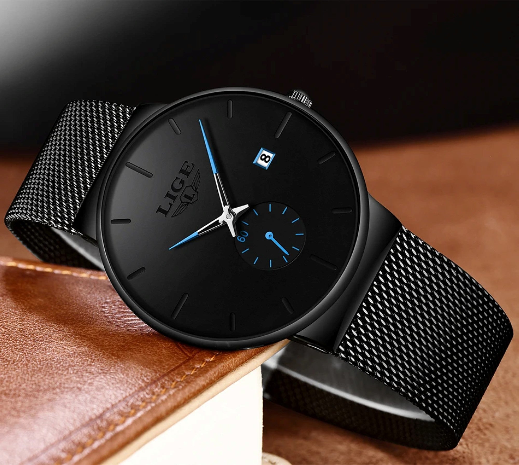 Black wristwatch with mesh band on a brown leather surface