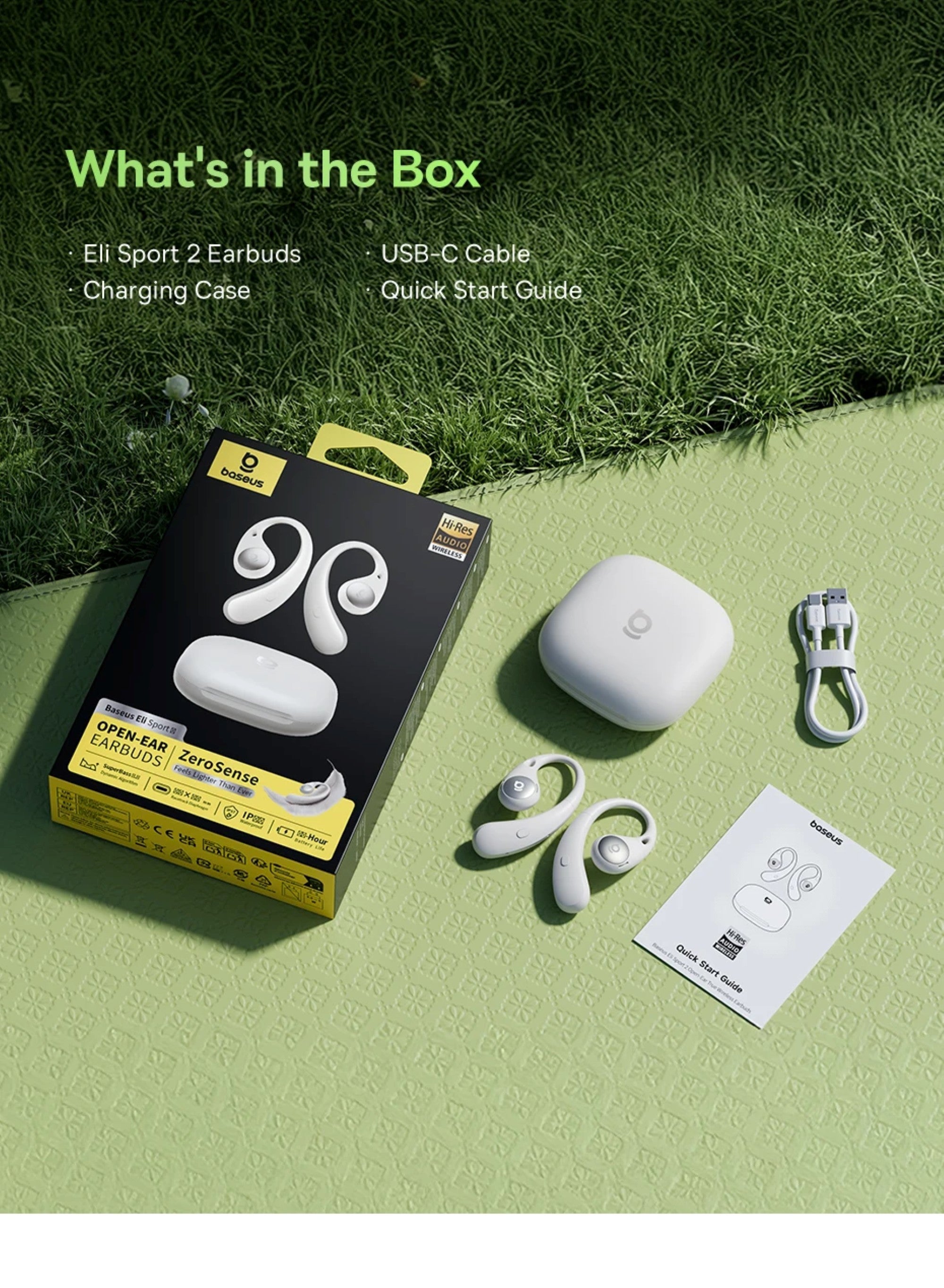 Box of earbuds with earbuds, charging case, USB-C cable, and quick start guide on a grassy background
