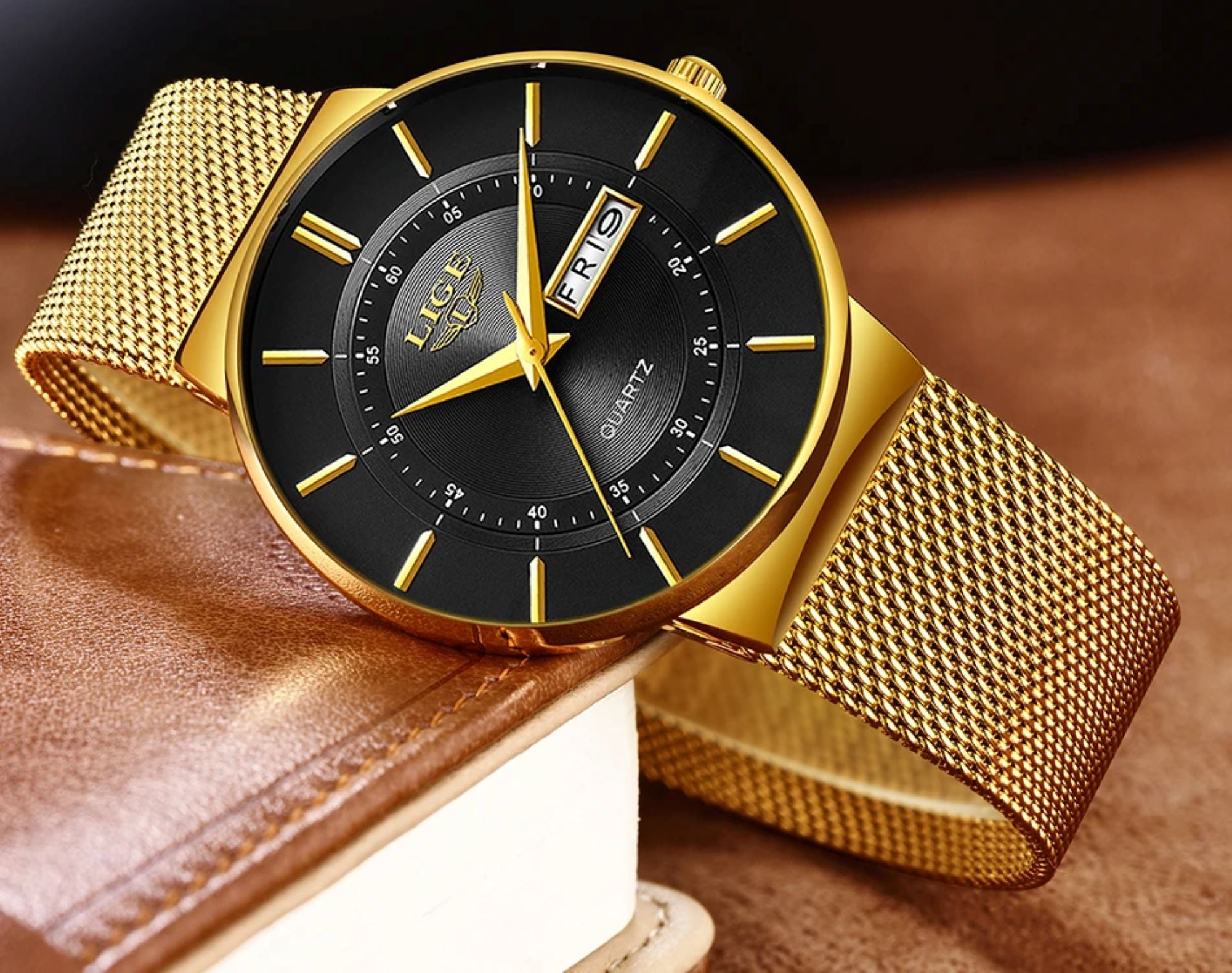Gold watch with black face on a brown leather surface