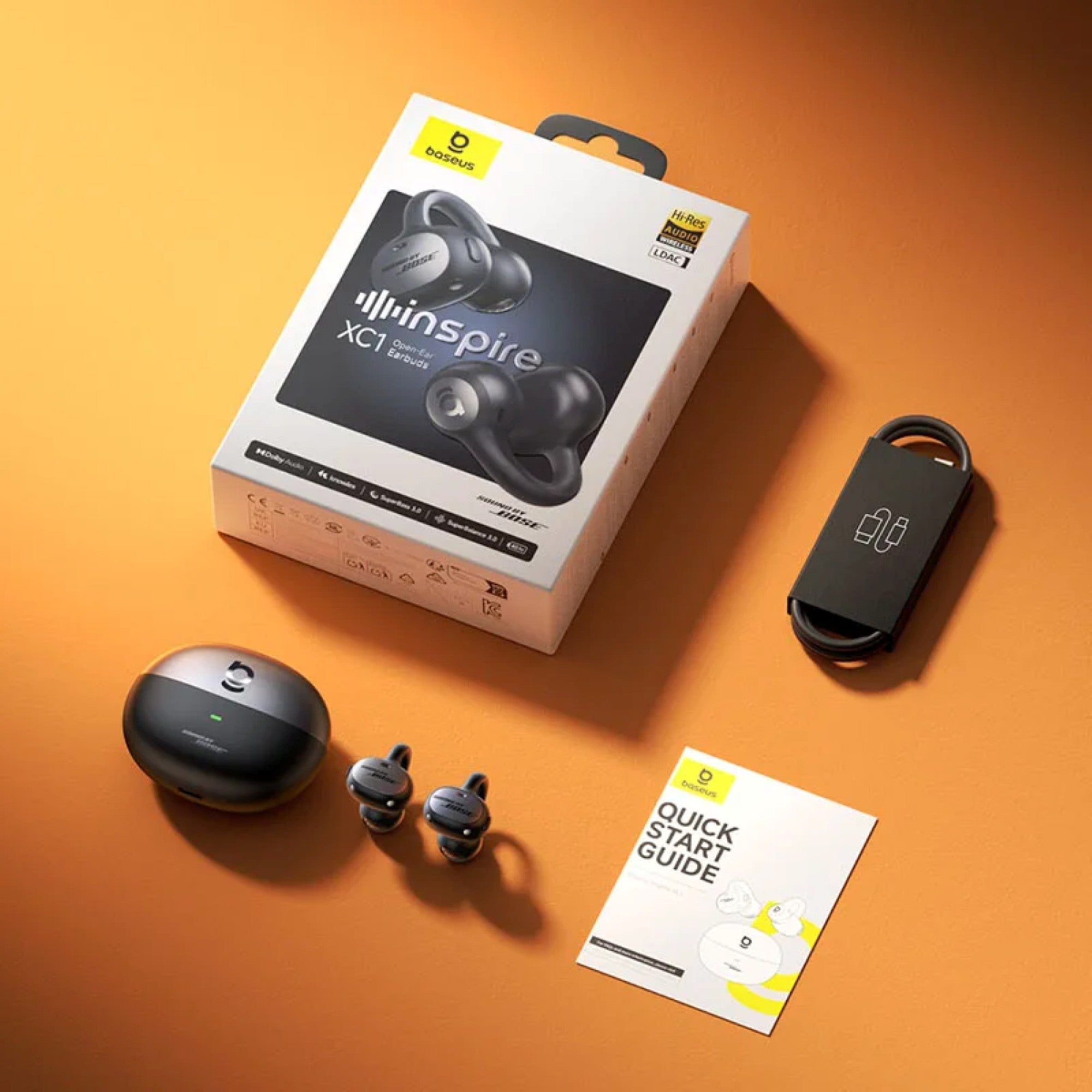 Hanspire XCI wireless earbuds with packaging, case, and quick start guide on an orange background