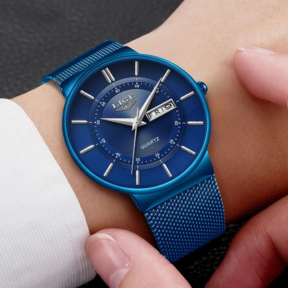 Blue watch with mesh band on a wrist against a dark background