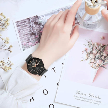 Hand wearing a black wristwatch on a decorative surface with flowers and cards.