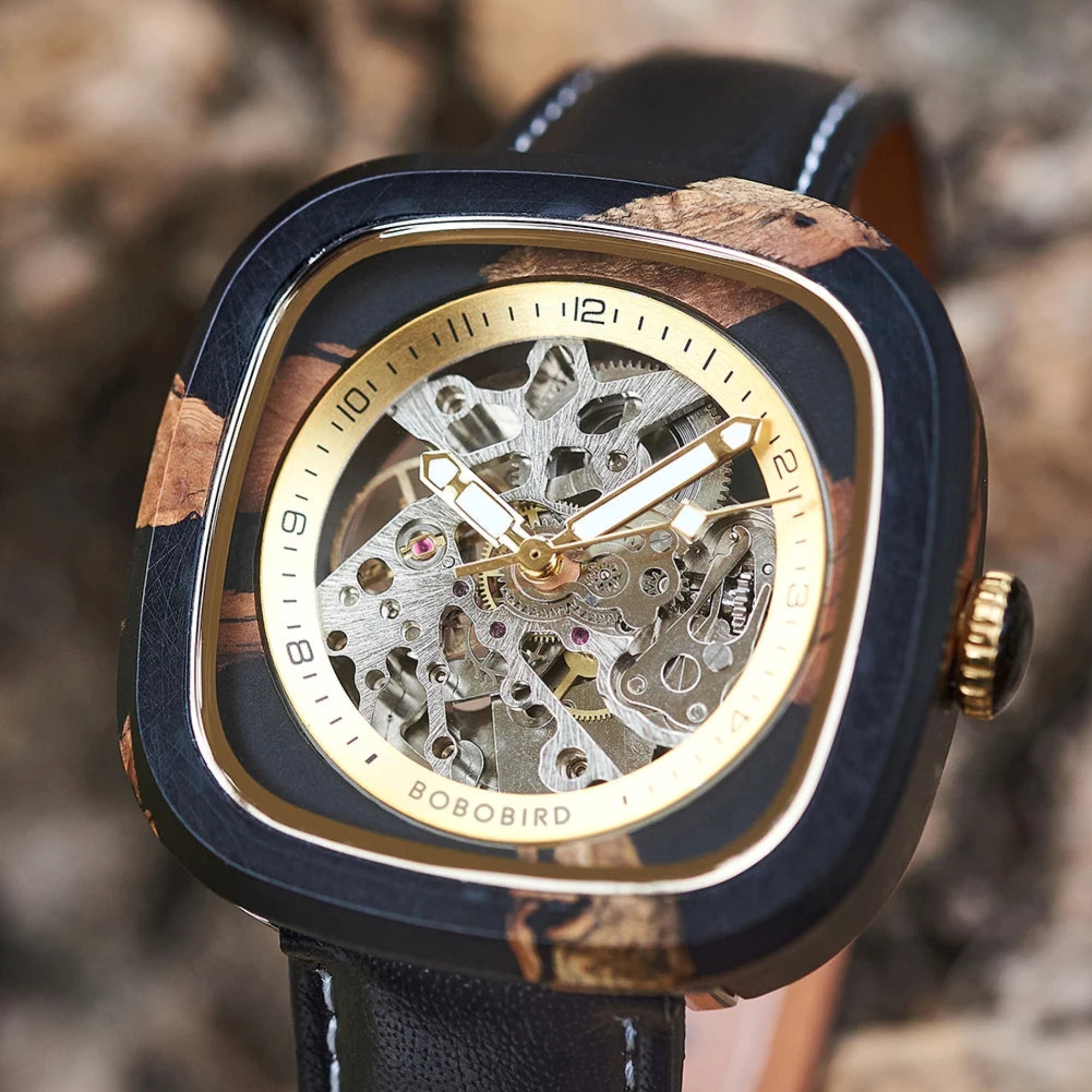 Luxury watch with wooden and black casing on a blurred natural background