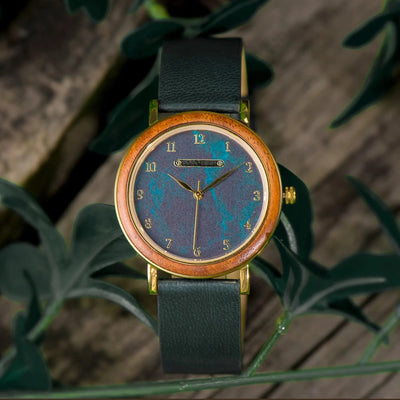 Watch with a wooden case and blue face on a green leafy background