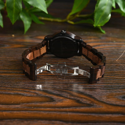 Wooden wristwatch on a wooden surface with leaves in the background