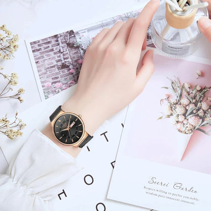 Hand wearing a black watch with a decorative background featuring flowers and cards.