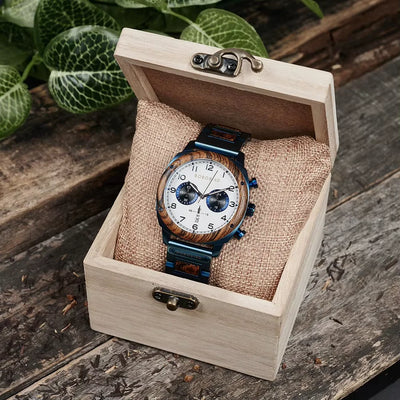 Wooden watch with brown strap in a wooden box on a rustic wooden surface.