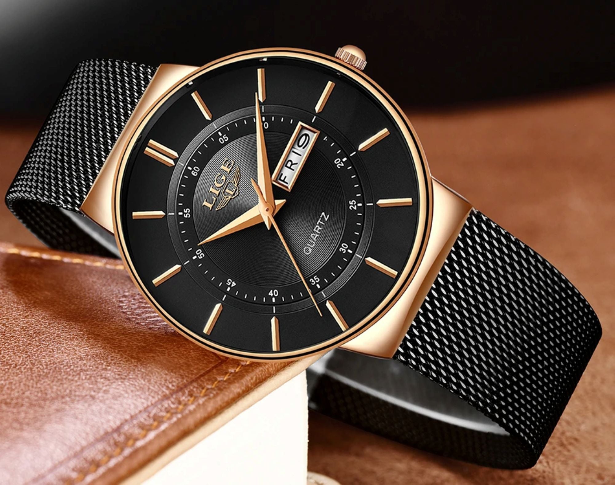 Luxury watch with black face and mesh band on a brown leather surface