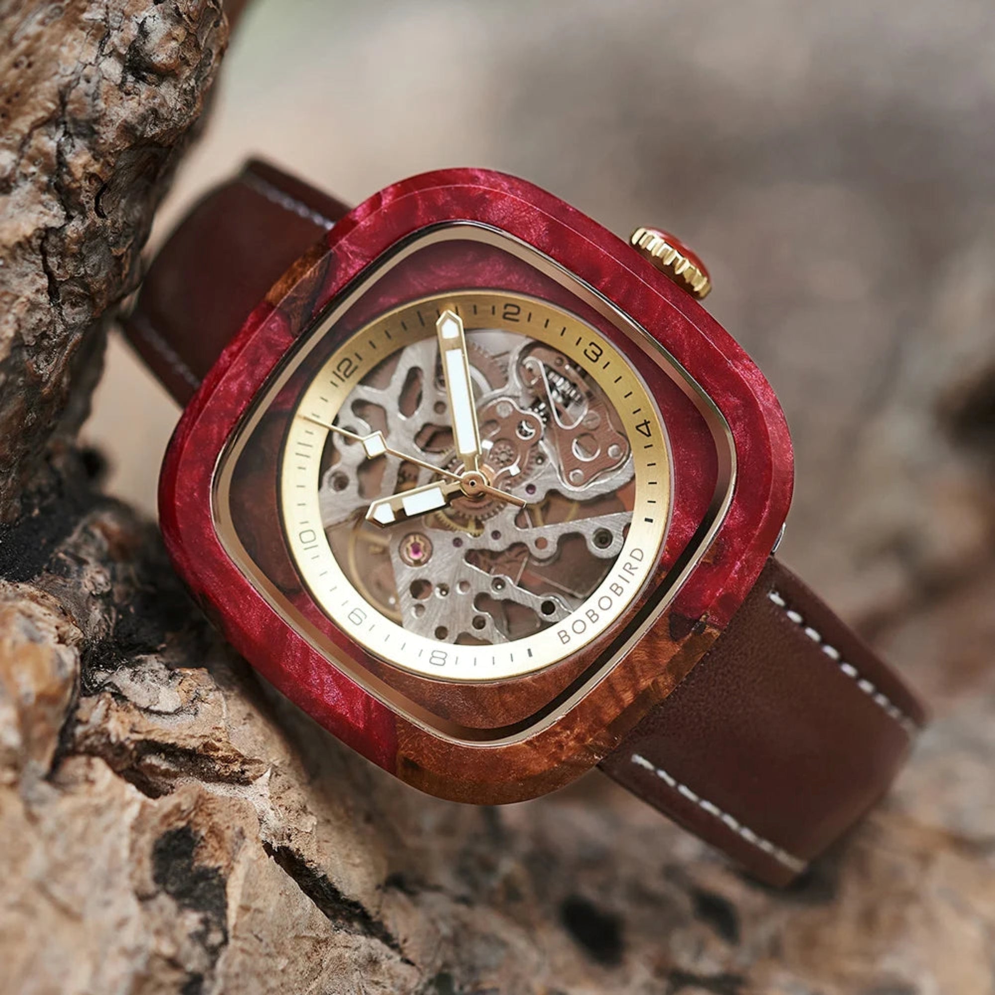 Watch with red wooden casing and brown leather strap on a textured 