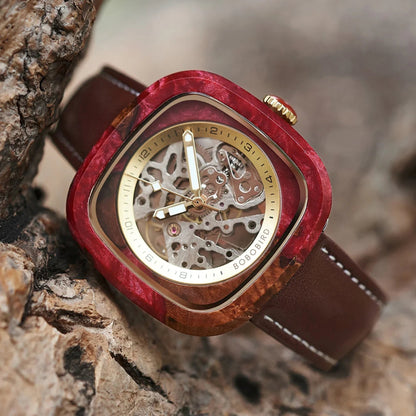 Watch with red wooden casing and brown leather strap on a textured 