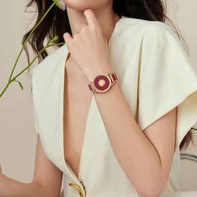 A woman wearing a white shirt showcasing a red and white resin EUTOUR watch with a gold-colored bracelet.