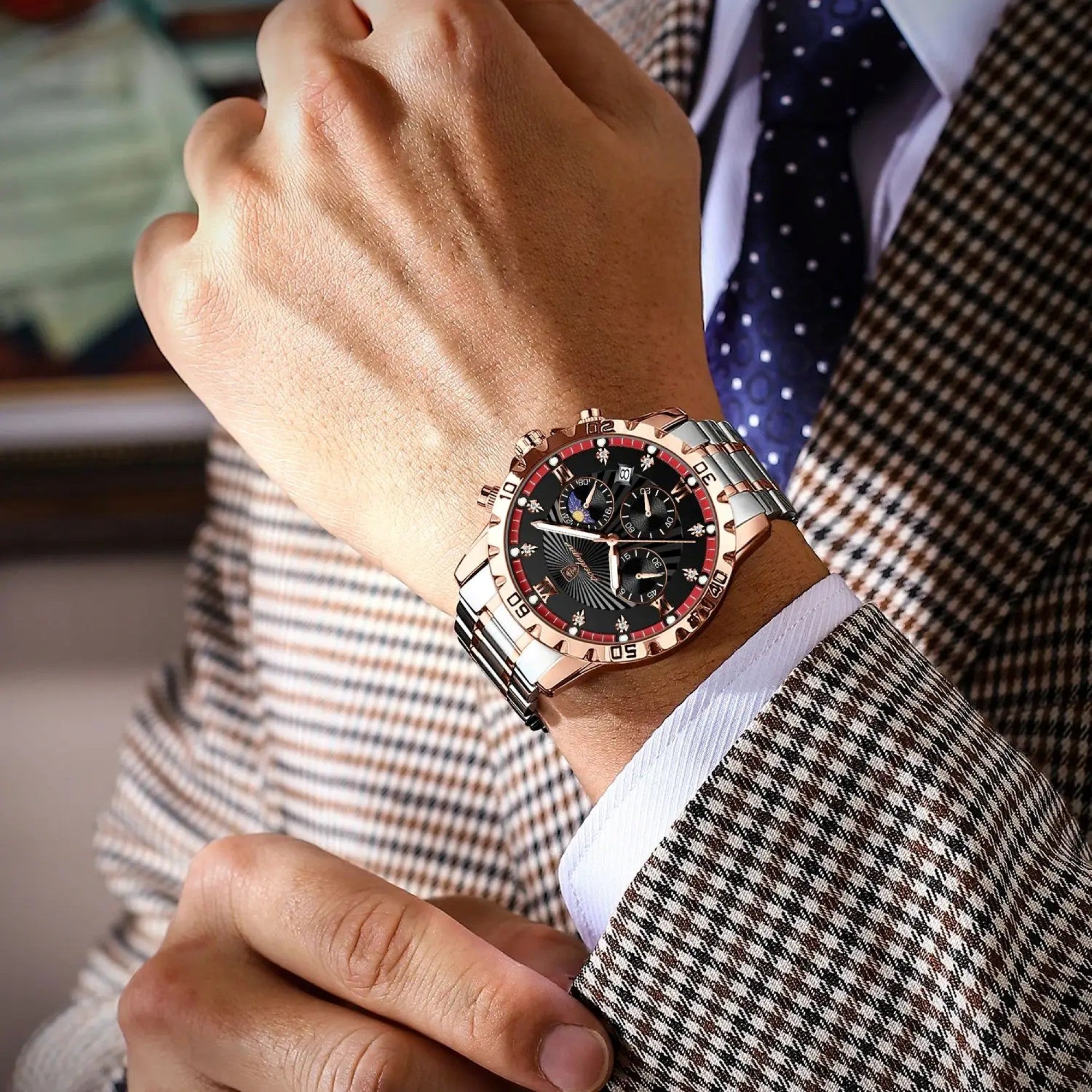 Close-up of a person wearing a stylish watch with a detailed face, dressed in a suit.