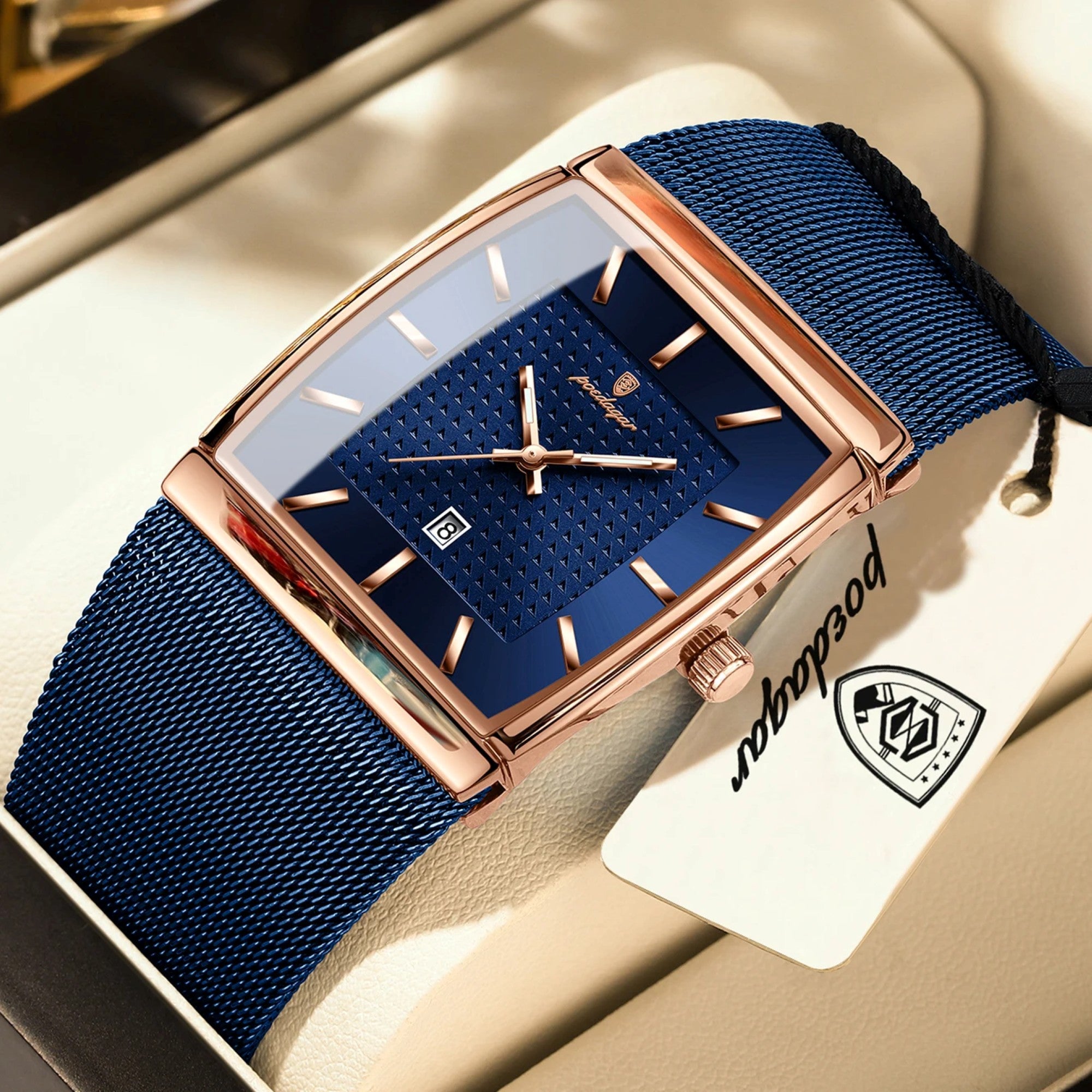 Luxury watch with blue strap and rose gold case on a beige surface, featuring a brand tag.