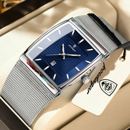 Silver watch with blue face on a beige surface, featuring a brand tag.