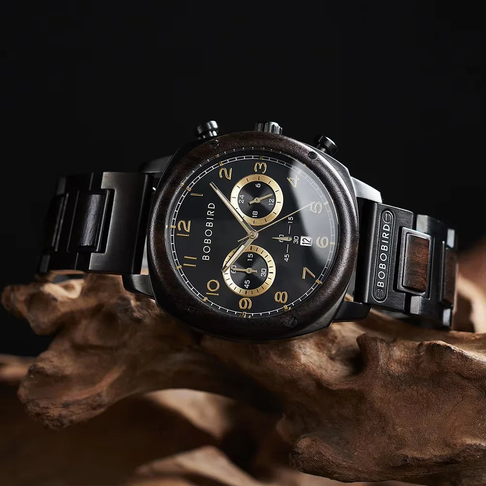 A Bobo Bird chronograph watch with a dark wood-grain dial and black metal bracelet, displayed on a piece of natural driftwood against a dark background.