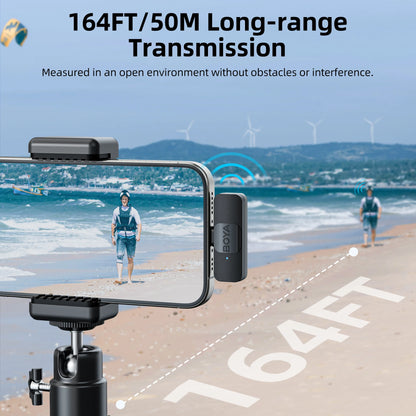 Phone with BOYA BY-DM1000 microphone on a tripod, showing long-range transmission on screen with wind turbines in the background.