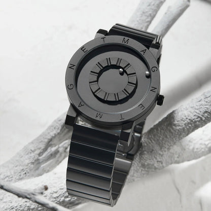 Black wristwatch with metallic band on a textured white surface