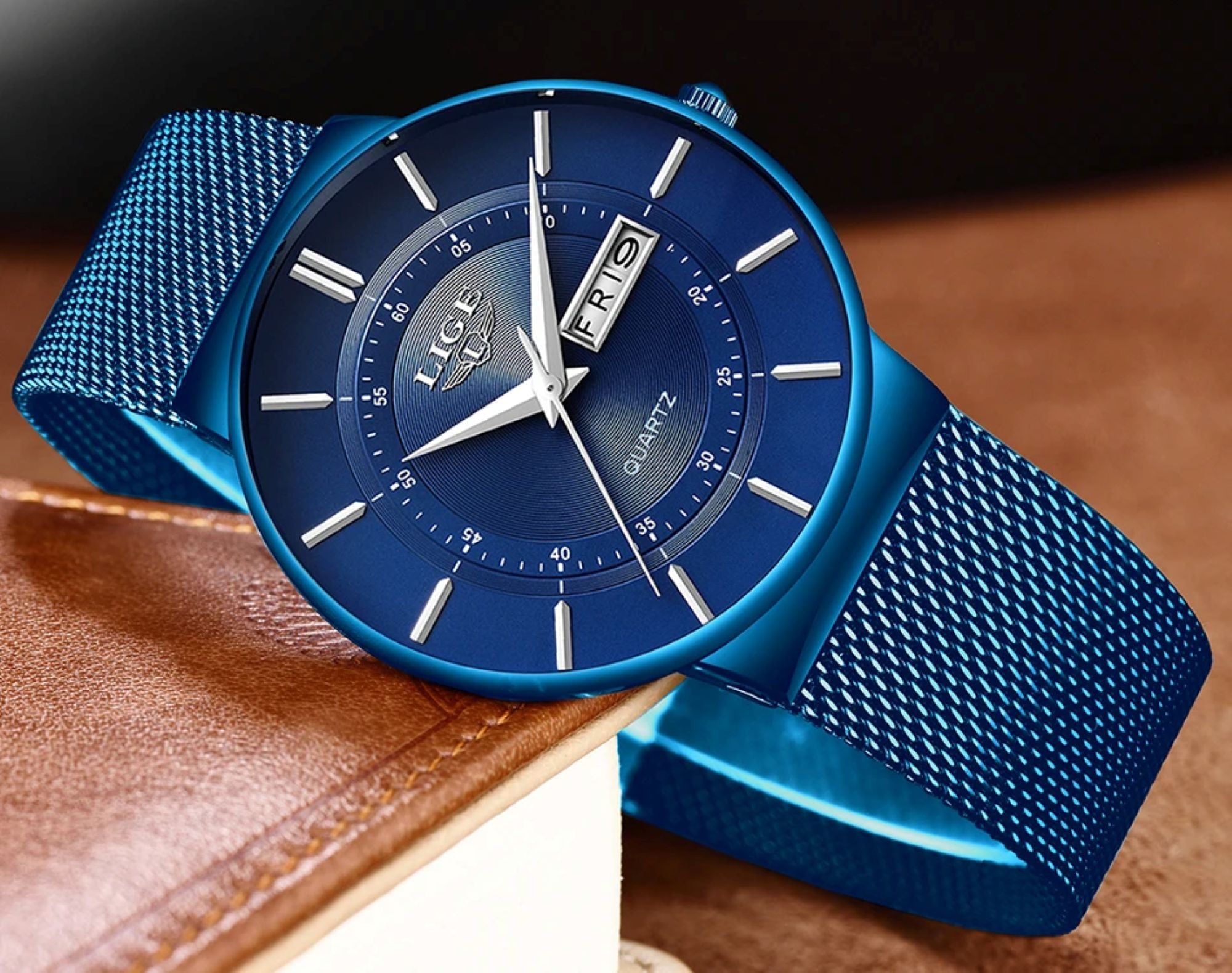 Blue wristwatch with mesh band on a brown leather surface