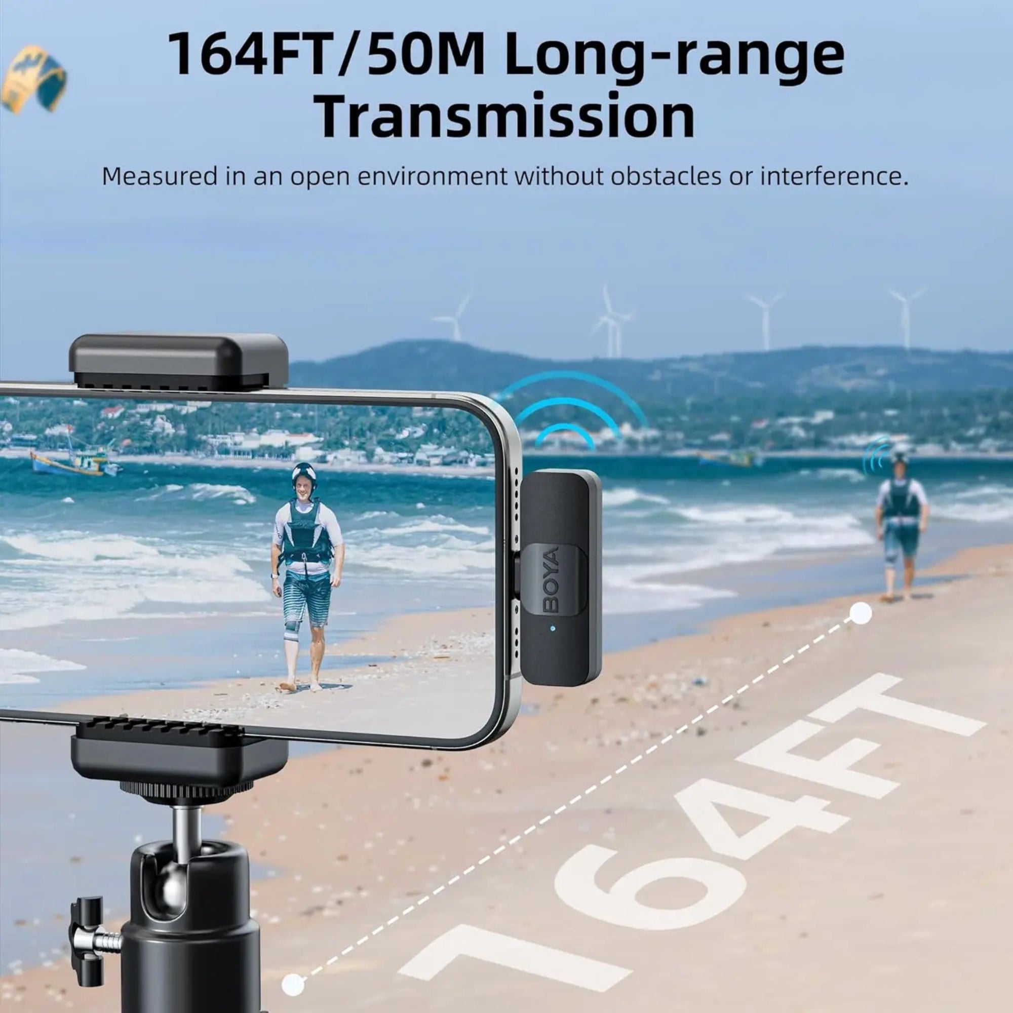 Phone with a BOYA microphone on a tripod, displaying a person on a beach with wind turbines in the background.
