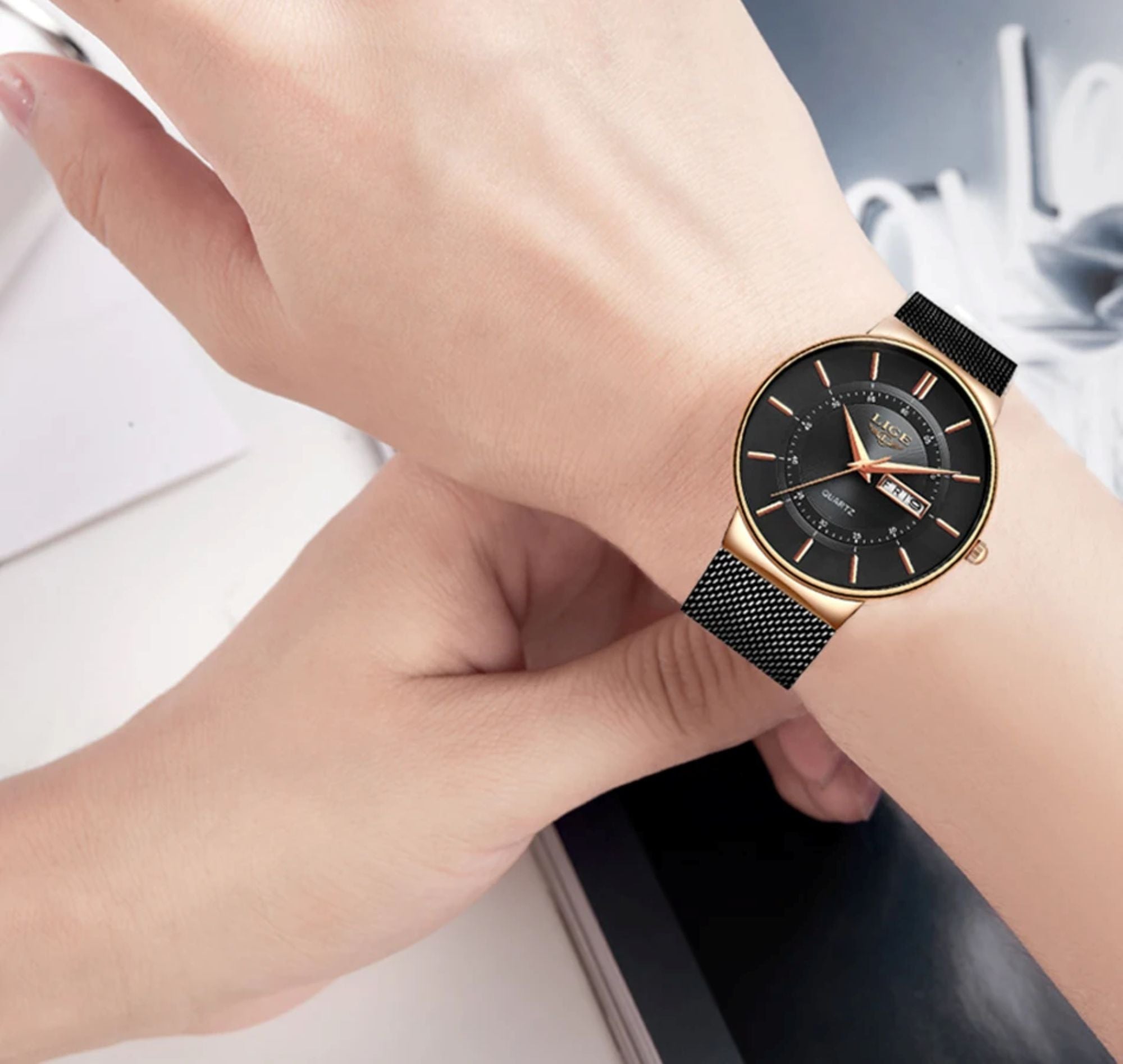 Hand wearing a black and gold watch with a blurred background