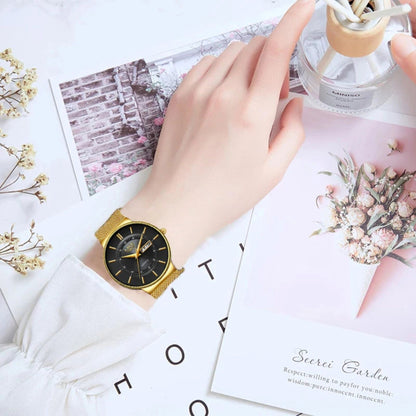 Gold watch on a wrist with a decorative background featuring flowers and cards.