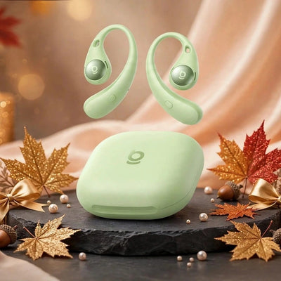 Mint green Baseus Eli Sport 2 open-ear wireless earbuds floating above matching oval charging case on black slate with glitter gold autumn leaves, gold bows, pearls and champagne silk