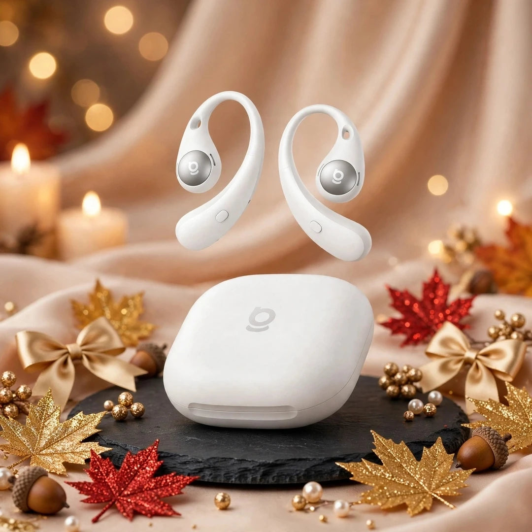 White Baseus Eli Sport 2 open-ear earbuds floating above white oval charging case on black slate with gold and red glitter maple leaves, gold bows, candles and warm autumn decor