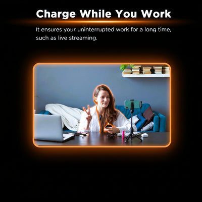 Woman live streaming from a desk with a phone and laptop, text 'Charge While You Work' at the top.