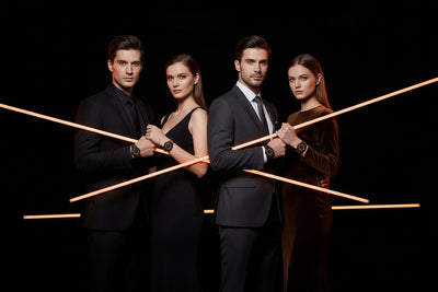 Four people in formal attire standing together with neon light bars on a black background