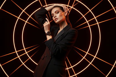 Woman in a black suit posing against a dark background with circular light patterns