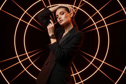 Woman in a black suit posing against a dark background with circular light patterns
